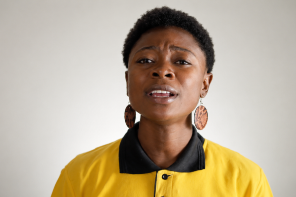 woman in yellow shirt speaking to camera